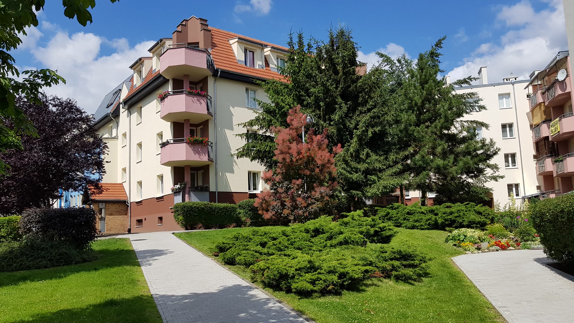 Budynek mieszkalny na osiedlu Zielone Wzgórza, przed nim chodnik i zadbana zieleń